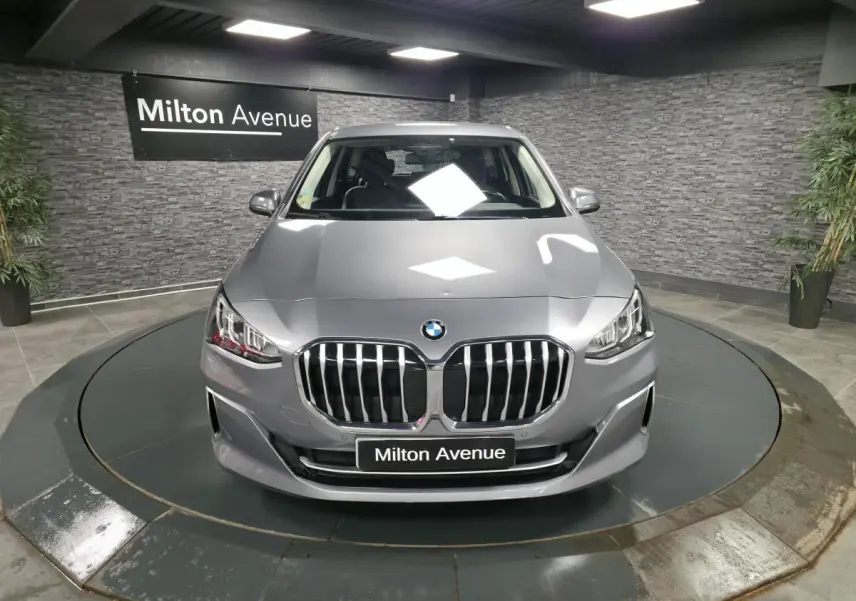 Vue avant d'une BMW Série 2 218d Active Tourer gris métallisé avec calandre chromée et phares LED en showroom.