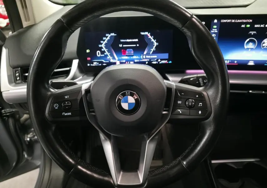 Vue rapprochée du volant cuir noir multifonctions de la BMW Série 2 218d Active Tourer avec tableau de bord numérique.
