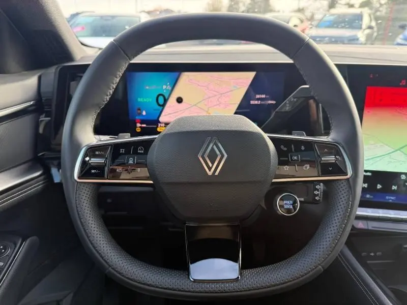 Vue rapprochée du volant noir perforé du Renault Austral 2025 avec logo central et écran numérique en arrière-plan.