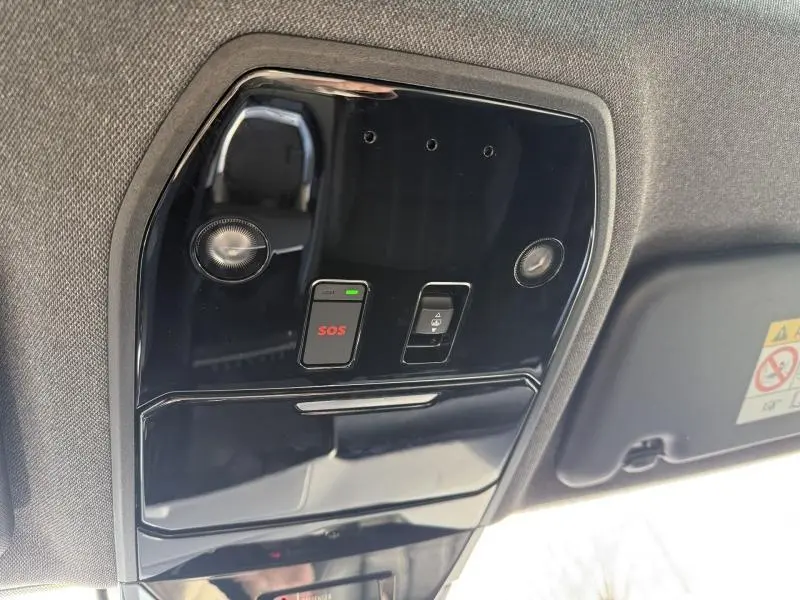 Vue intérieure en gros plan du plafonnier noir brillant avec bouton SOS du Renault Austral 2025 blanc nacré et toit noir étoilé.