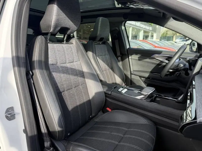 Vue intérieure côté conducteur du Renault Austral 2025 avec sièges tissu et cuir gris, planche de bord moderne et toit panoramique.