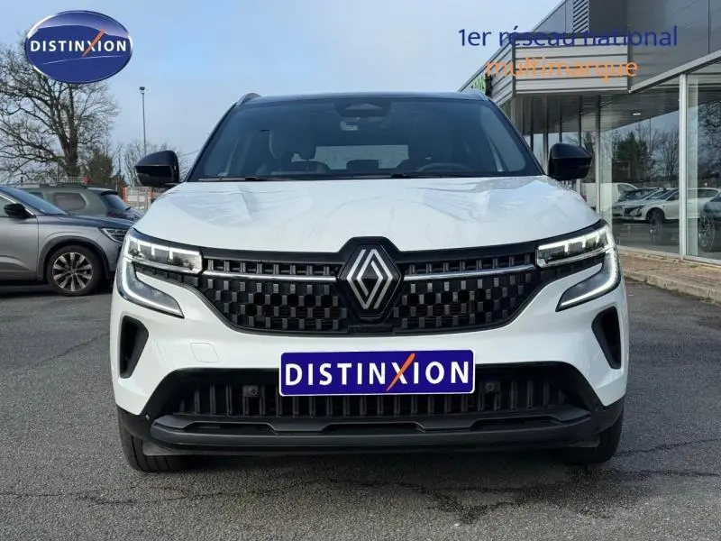 Vue de face du Renault Austral blanc nacré avec toit noir étoilé, mettant en valeur la calandre noire et les phares LED distinctifs.