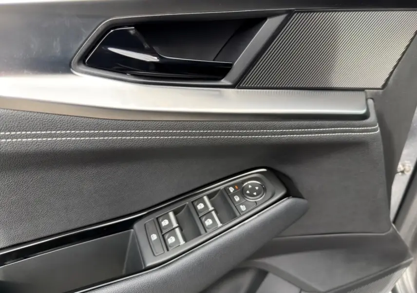 Gros plan sur la porte avant gauche gris foncé du Renault Austral avec commandes électriques des vitres et rétroviseurs.