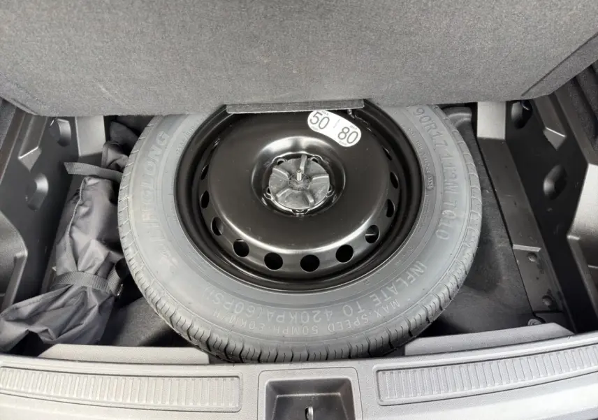 Vue plongeante sur la roue de secours noire dans le coffre du Renault Austral gris foncé 2025.