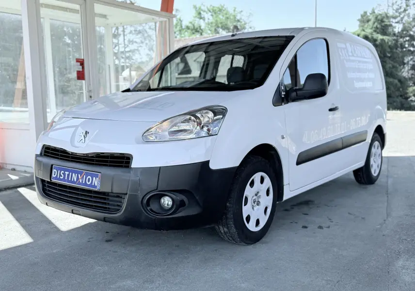 Vue 3/4 avant droit d’un Peugeot Partner blanc utilitaire avec pare-chocs noir et marquage publicitaire sur la porte latérale.