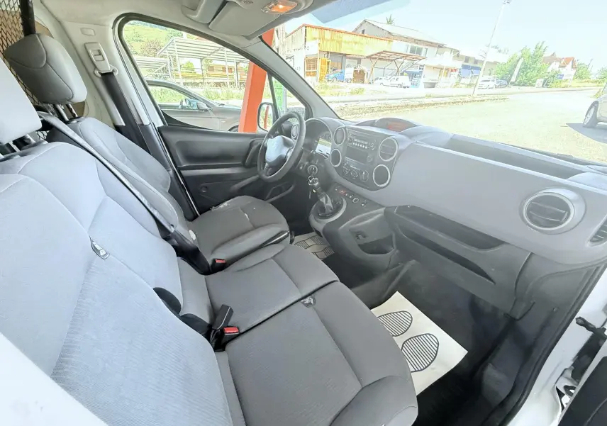 Vue intérieure côté conducteur du Peugeot Partner blanc 2014, montrant les sièges avant et le tableau de bord avec boîte manuelle.