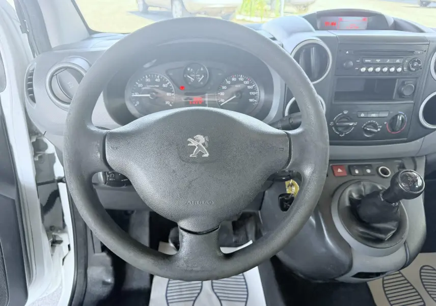Vue intérieure du tableau de bord et volant noir du Peugeot Partner blanc 2014 avec levier de vitesse manuel visible.