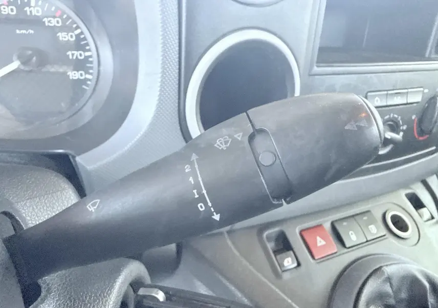 Gros plan sur la manette d’essuie-glace à gauche du tableau de bord du Peugeot Partner blanc de 2014.