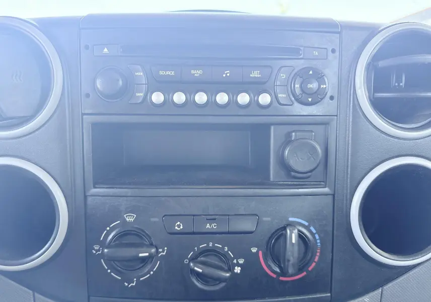 Tableau de bord du Peugeot Partner 1.6 HDI 2014 montrant la console centrale avec commandes de climatisation et autoradio.