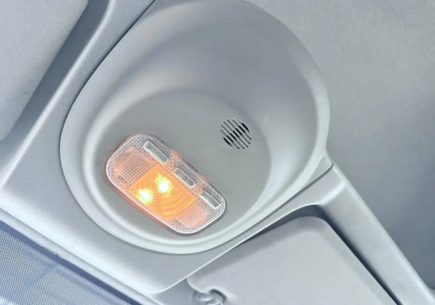 Plafonnier intérieur allumé avec haut-parleur intégré sur le toit d'un Peugeot Partner blanc de 2014.