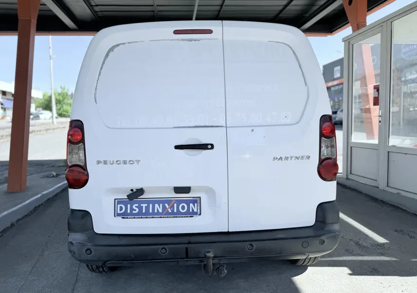 Vue arrière d'un Peugeot Partner blanc de 2014 avec portes battantes et pare-chocs noir sous un abri.