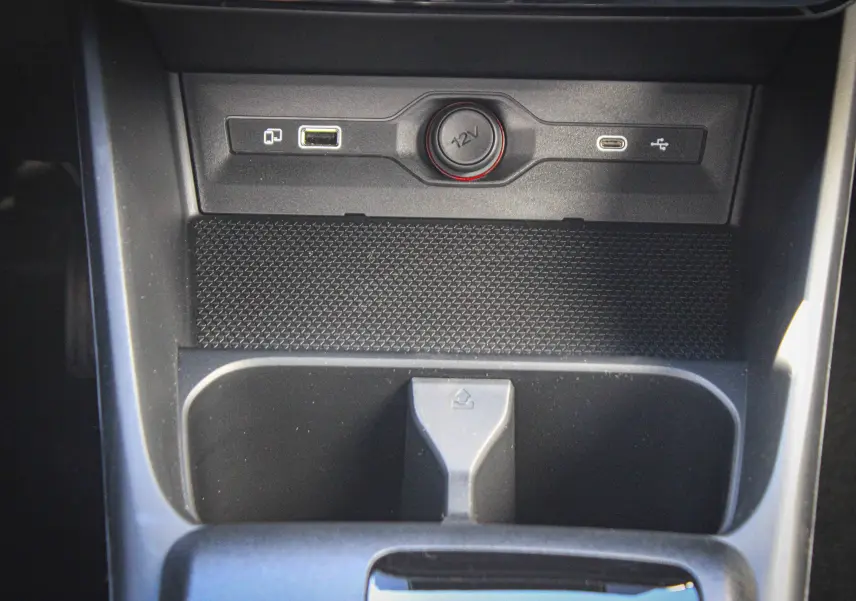 Gros plan sur la console centrale du MG3 1.5L Hybrid+ 195ch Luxury, montrant prises USB, prise 12V et rangement noir.