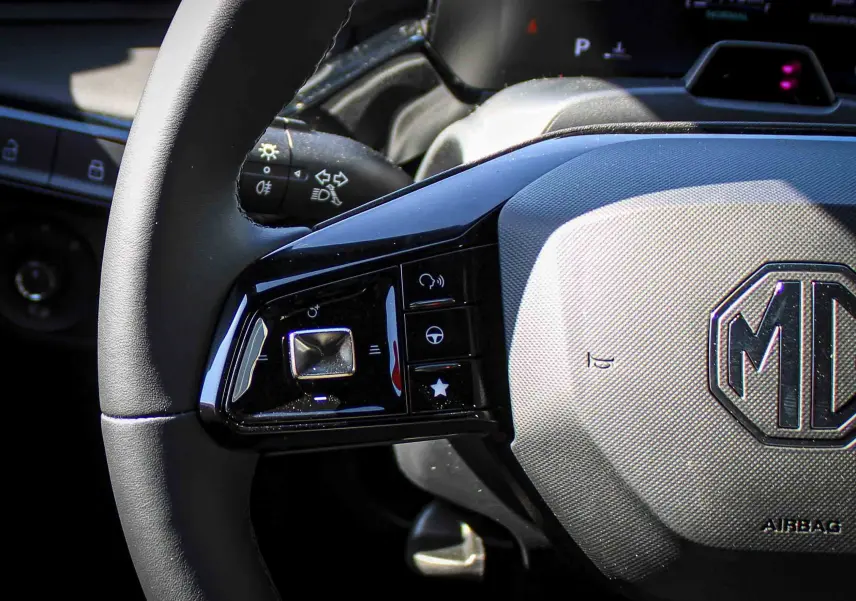 Gros plan sur le volant gris texturé du MG3 2026, avec commandes tactiles noires et logo MG central visible.