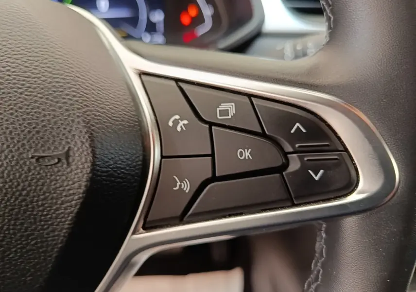 Gros plan sur les commandes multifonctions du volant cuir synthétique du Renault Captur Business E-Tech hybride gris clair.