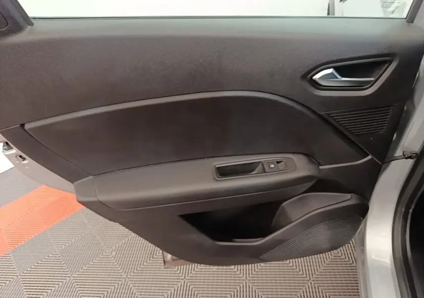 Vue rapprochée de la porte avant droite grise du Renault Captur Business E-Tech hybride avec commandes de fenêtre et poignée intégrée.
