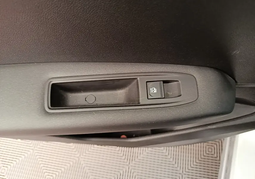 Gros plan sur le bouton de verrouillage des vitres sur la porte intérieure noire d’un Renault Captur gris clair.