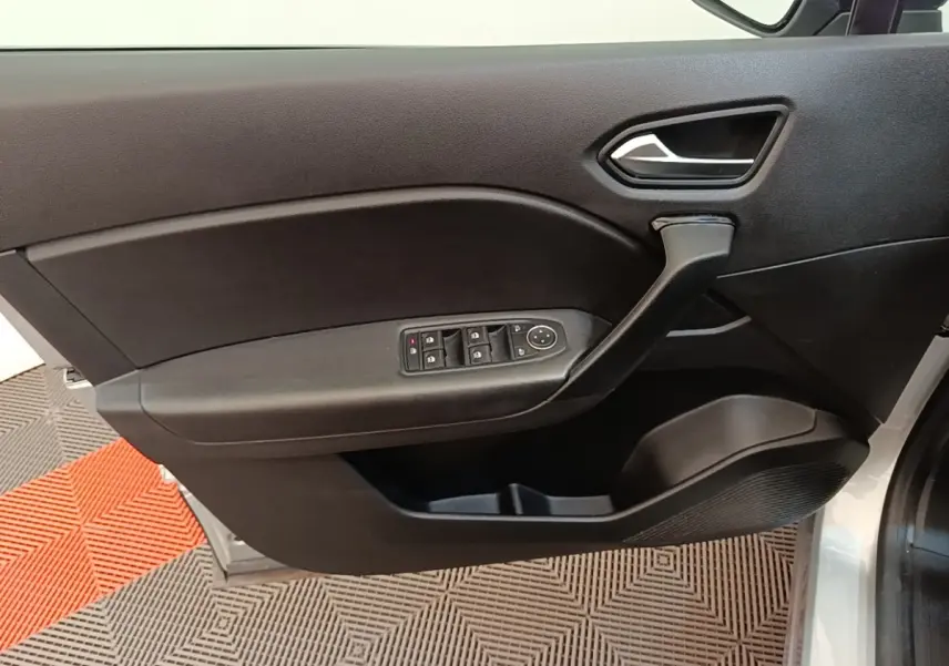 Vue rapprochée de la porte avant gauche noire du Renault Captur gris clair, avec commandes électriques des vitres.