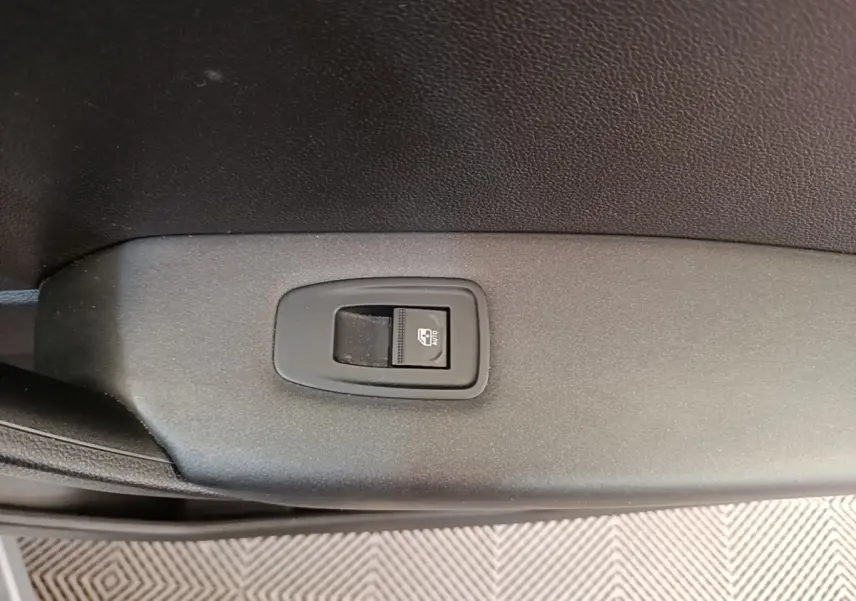 Gros plan sur le bouton de commande de la vitre électrique côté conducteur du Renault Captur Business E-Tech gris clair.