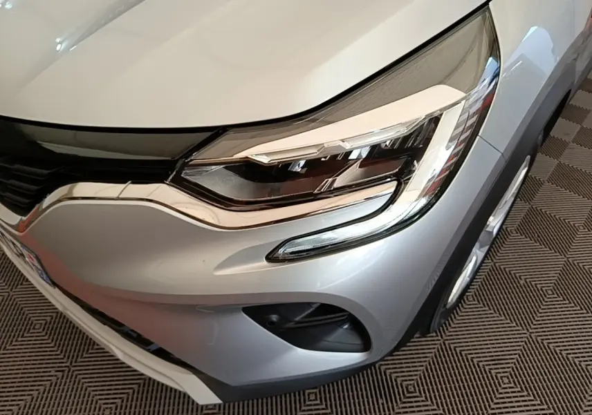 Gros plan sur l'avant droit gris clair du Renault Captur Business E-Tech hybride 2022, mettant en valeur le phare LED et la calandre.