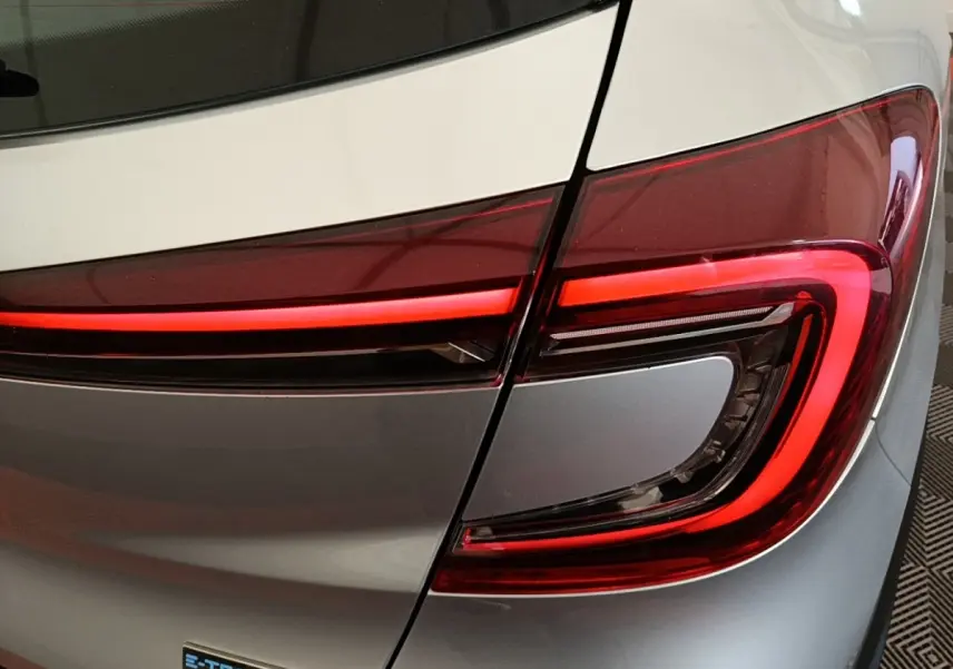 Gros plan sur le feu arrière droit rouge et noir d’un Renault Captur Business E-Tech gris clair 2022.