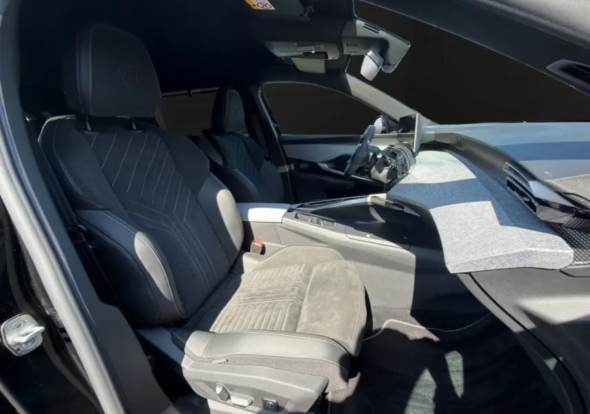 Vue intérieure côté conducteur du Peugeot 5008 noir 2025, sièges Alcantara et tableau de bord moderne avec écran tactile.