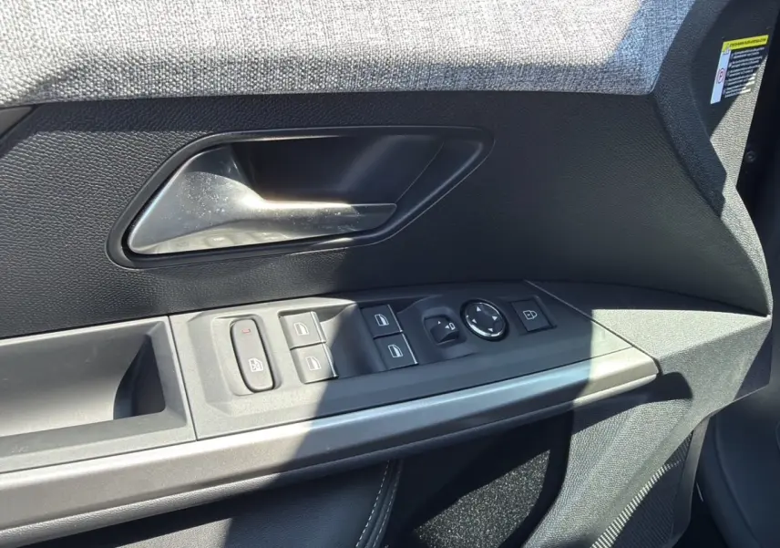 Gros plan sur la porte intérieure côté conducteur du Peugeot 5008 noir, montrant les commandes des vitres et rétroviseurs.