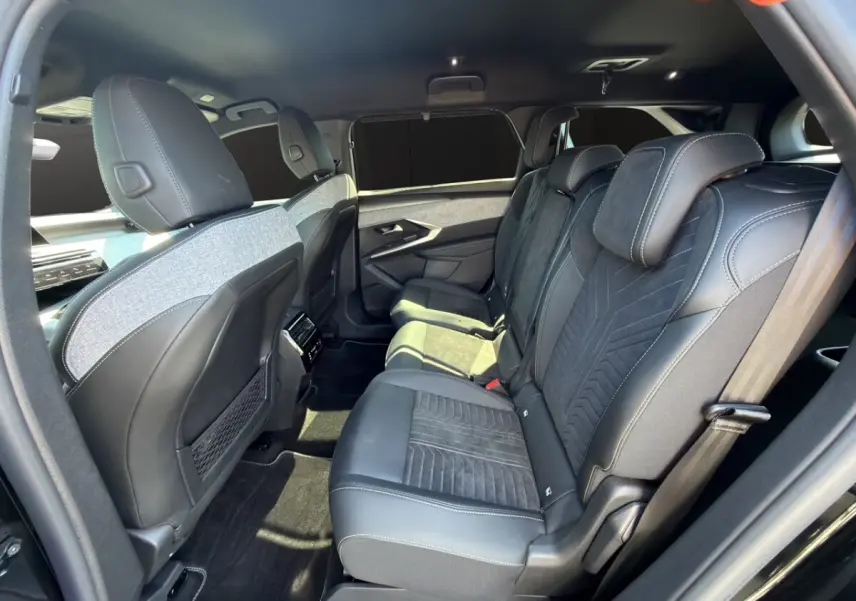 Vue latérale droite de l'intérieur arrière du Peugeot 5008 noir, sièges en Alcantara avec surpiqûres blanches.