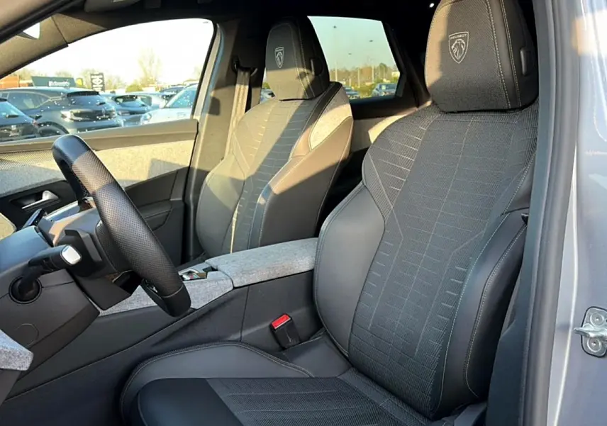Intérieur Peugeot 3008 gris, vue côté conducteur montrant sièges sport avec logo Peugeot brodé sur les appuis-tête.