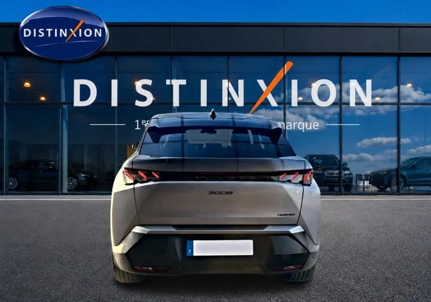 Vue arrière d’un Peugeot 3008 gris 2025 avec feux arrière LED distinctifs, stationné devant une vitrine Distinxion.