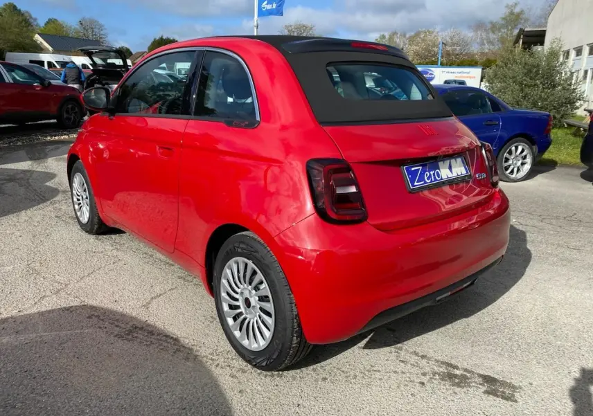 Vue 3/4 arrière droite d'une FIAT 500 Cabriolet électrique rouge avec toit noir et jantes alliage 16 pouces.