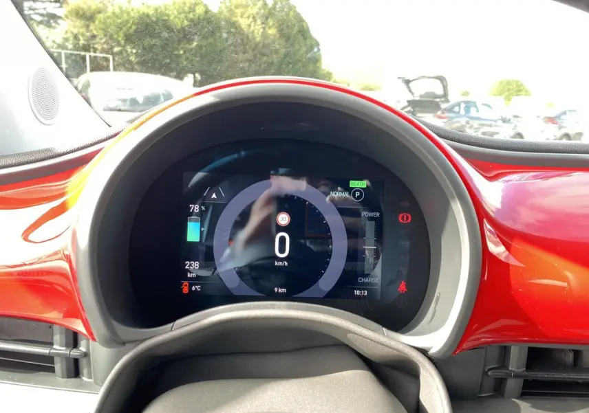 Tableau de bord numérique de la Fiat 500 Cabriolet Electrique rouge, affichant vitesse et autonomie, vue frontale rapprochée.