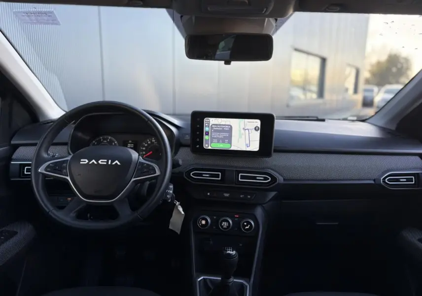 Vue intérieure avant du tableau de bord du Dacia Jogger gris, avec écran tactile GPS et volant multifonction.