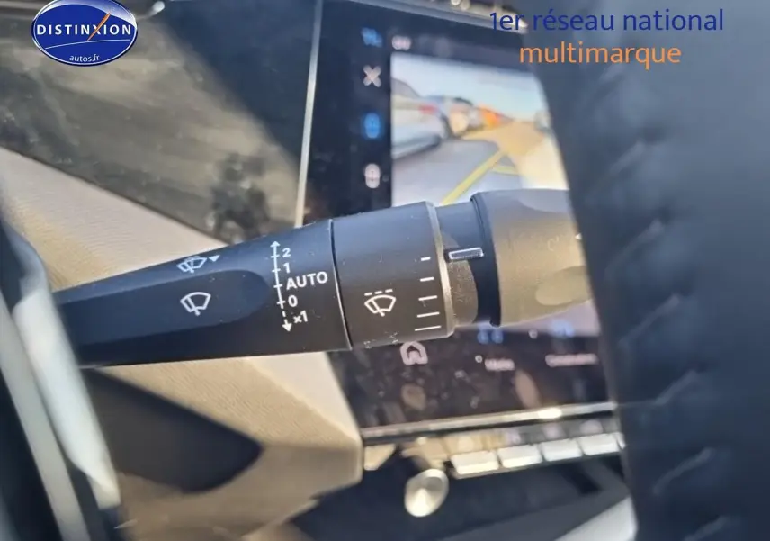 Gros plan sur la commande des essuie-glaces à gauche du volant cuir dans le Peugeot 408 noir, avec écran tactile en arrière-plan.