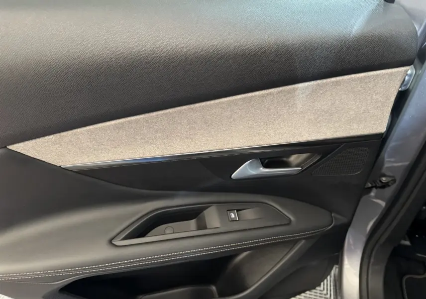 Vue rapprochée de la porte avant droite gris clair du Peugeot 3008 2021 avec garniture noire et beige et commande de vitre.