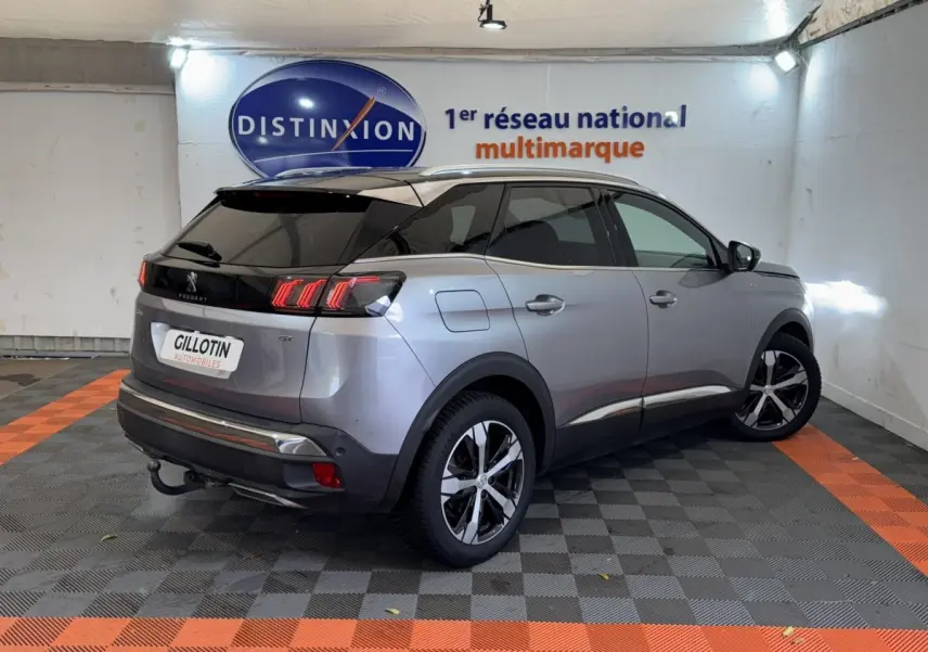 Vue 3/4 arrière droite d’un Peugeot 3008 GT gris clair avec toit noir et feux arrière LED distinctifs.