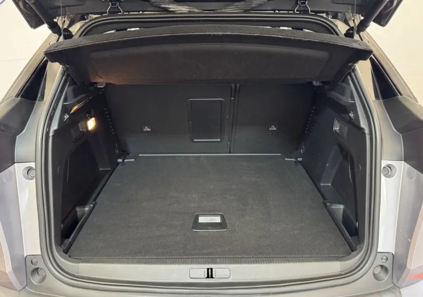 Coffre ouvert d’un Peugeot 3008 gris clair, vue arrière montrant l’espace de rangement vide et la tablette de couverture.