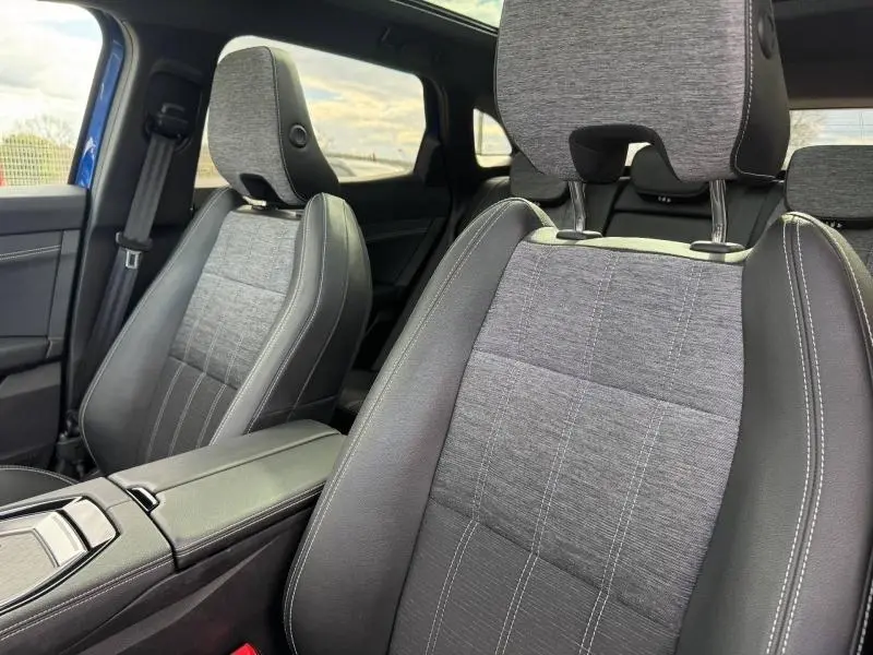 Vue rapprochée des sièges avant en tissu gris et cuir noir du Renault Austral 2025, intérieur moderne et soigné.