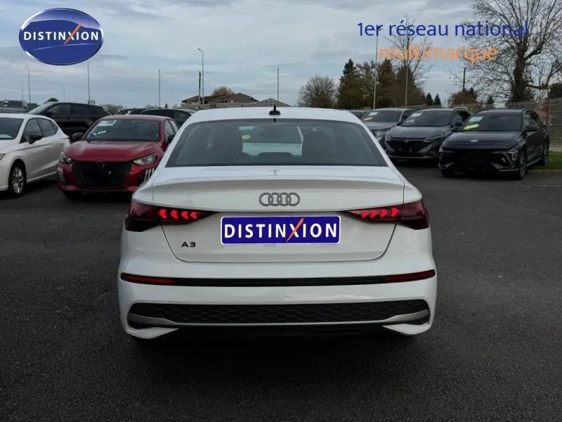 Vue arrière d'une Audi A3 Sportback blanche 2024 avec feux arrière LED et becquet discret sur parking.