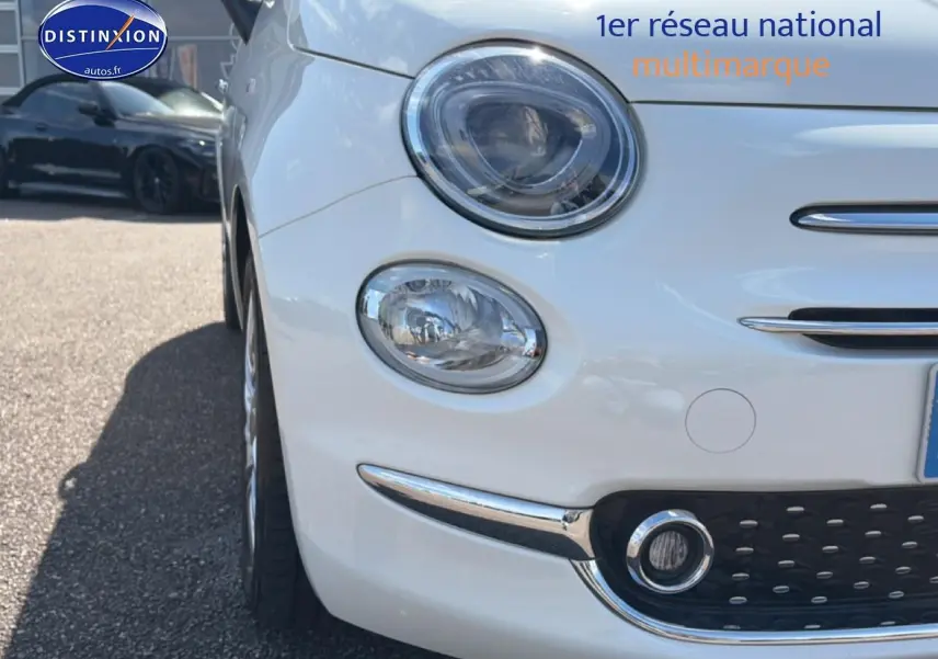 Gros plan sur l'avant gauche d'une Fiat 500 blanche 2023 avec phares ronds et détails chromés.