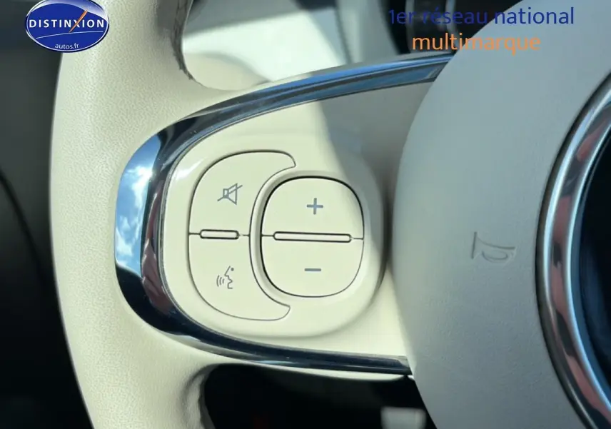 Gros plan sur les commandes audio et vocales blanches intégrées au volant de la FIAT 500 blanche 2023.
