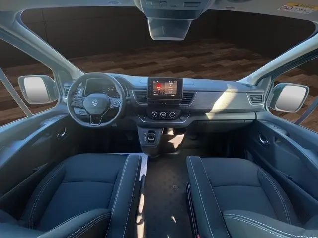 Vue intérieure avant du Renault Trafic Fourgon gris foncé, montrant le tableau de bord moderne avec écran tactile central et volant multifonctions.