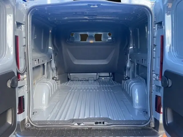 Vue intérieure arrière du fourgon Renault Trafic gris foncé, montrant l'espace de chargement vide avec cloison pleine.