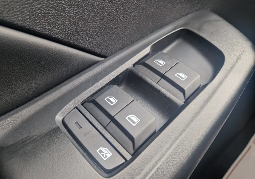 Gros plan sur les commandes électriques des vitres côté conducteur de la MG3 1.5L HYBRID+ 195CH LUXURY en intérieur noir.