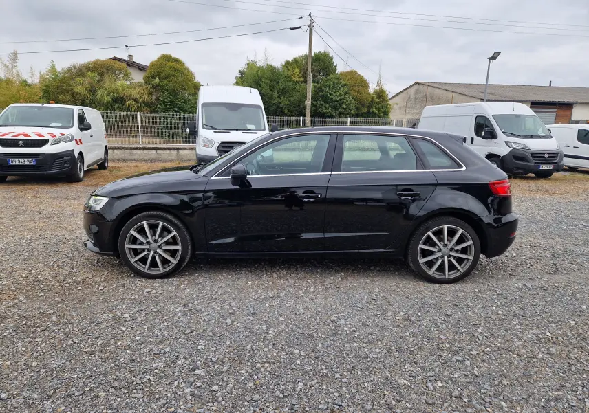Profil côté gauche d'une Audi A3 Sportback noire 2019, avec jantes alliage 18 pouces sur un sol gravillonné.