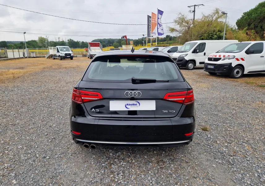 Vue arrière d’une Audi A3 Sportback noire 35 TDI 2019, avec double sortie d’échappement et feux arrière allumés.