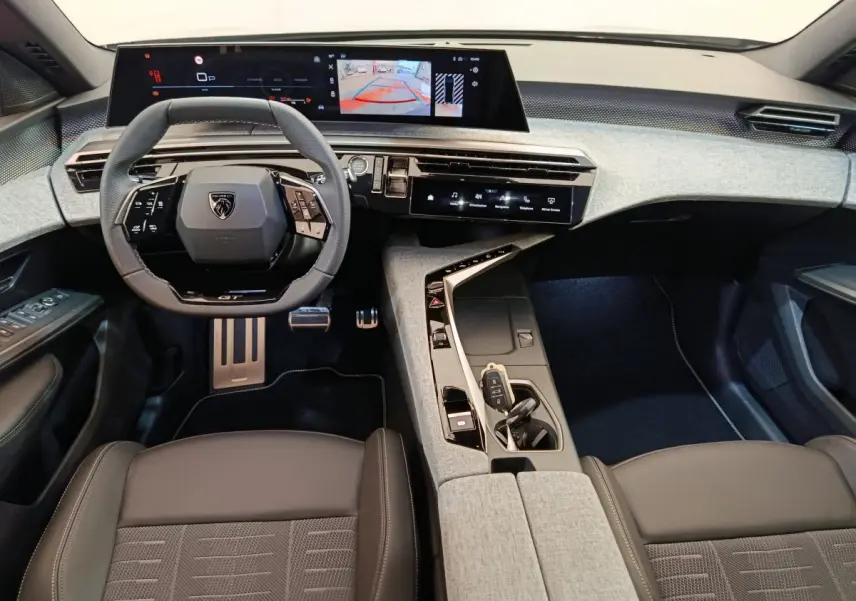Vue intérieure avant du Peugeot 3008 1.2 Hybrid 145 GT, avec volant compact, écran tactile large et finition tissu gris clair.