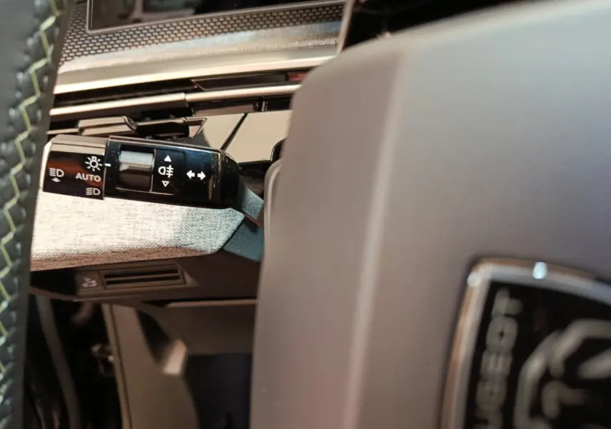 Gros plan sur la manette de commandes d’éclairage à gauche du volant du Peugeot 3008 noir, intérieur moderne.