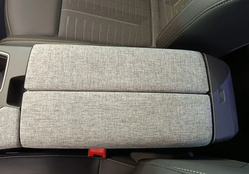Gros plan sur l'accoudoir central en tissu gris clair, entouré de sièges noirs du Peugeot 3008 2025.
