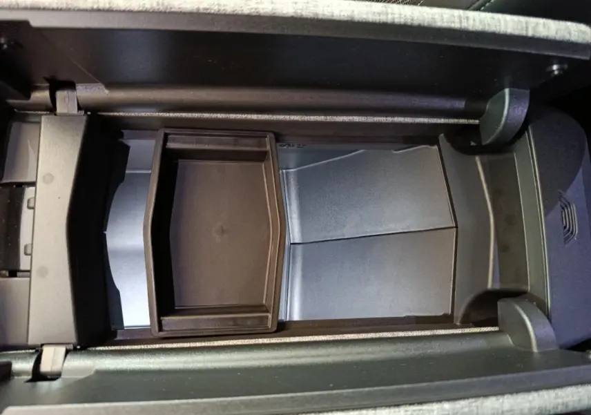 Vue plongeante sur le rangement central intérieur du Peugeot 3008 1.2 Hybrid 145 GT, avec compartiment noir et finition grise.