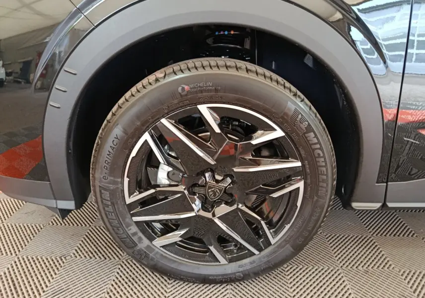 Gros plan sur la roue avant droite noire du Peugeot 3008 1.2 HYBRID 145 GT avec jante alliage bicolore et pneu Michelin.
